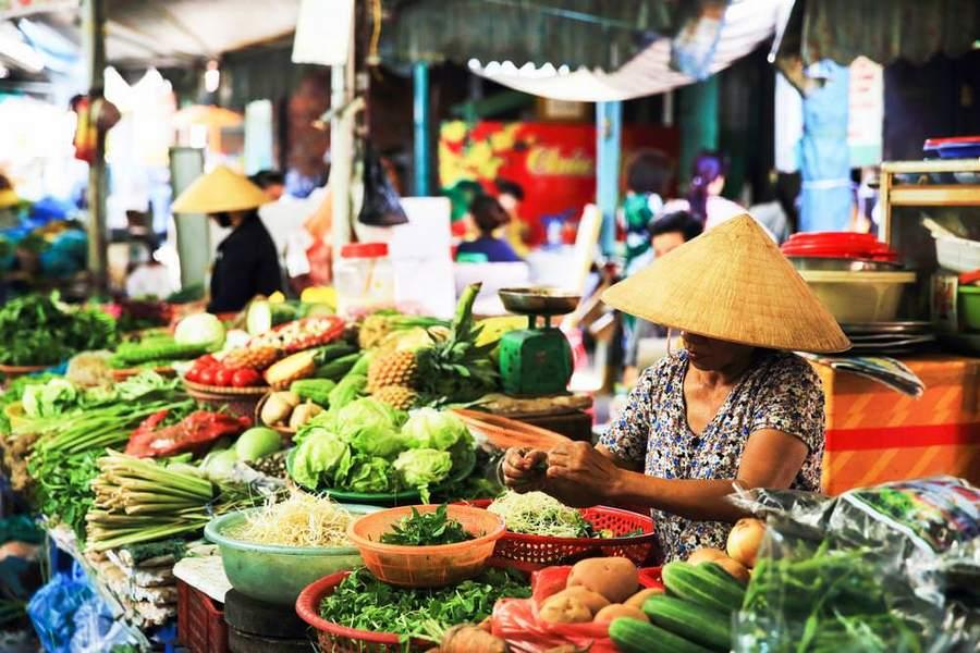 Vietnamese street market vendor with conical hat